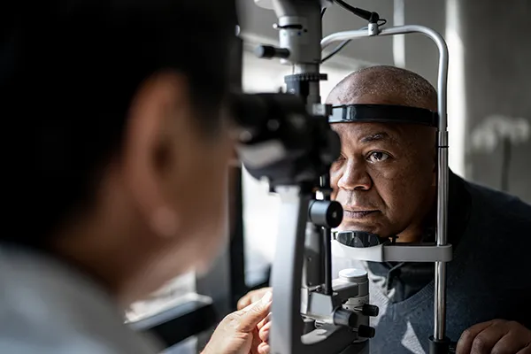 Male ophthalmologist uses a slit lamp to examine the eyes of