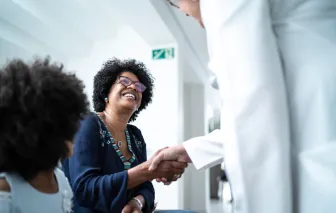 Female doctor welcoming and greeting mother and daughter at 