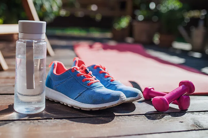 Close up of clear sports water bottle, blue sneakers with or