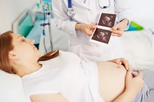 Doc standing next to pregnant woman explaining images
