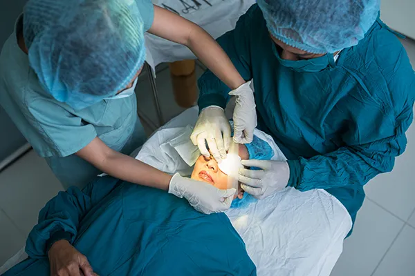 Two surgeons perform surgery on a patient’s eye in an operat