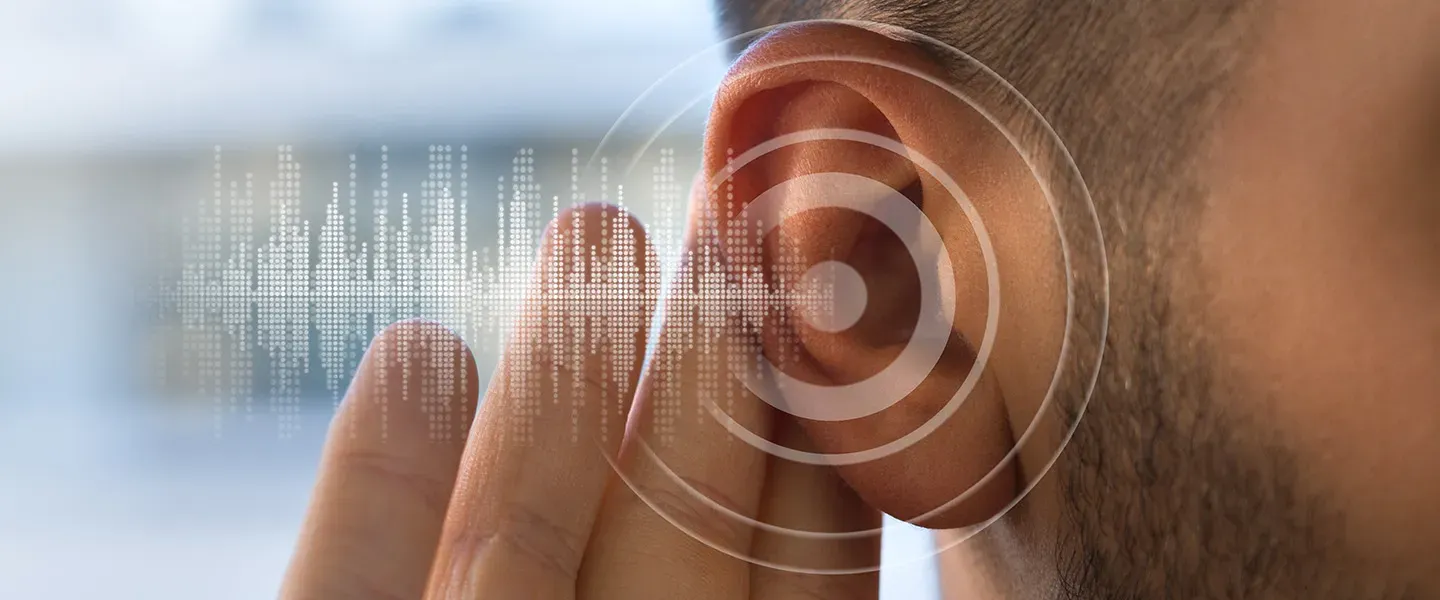 A man holds his hand up behind his ear as if listening. Tran