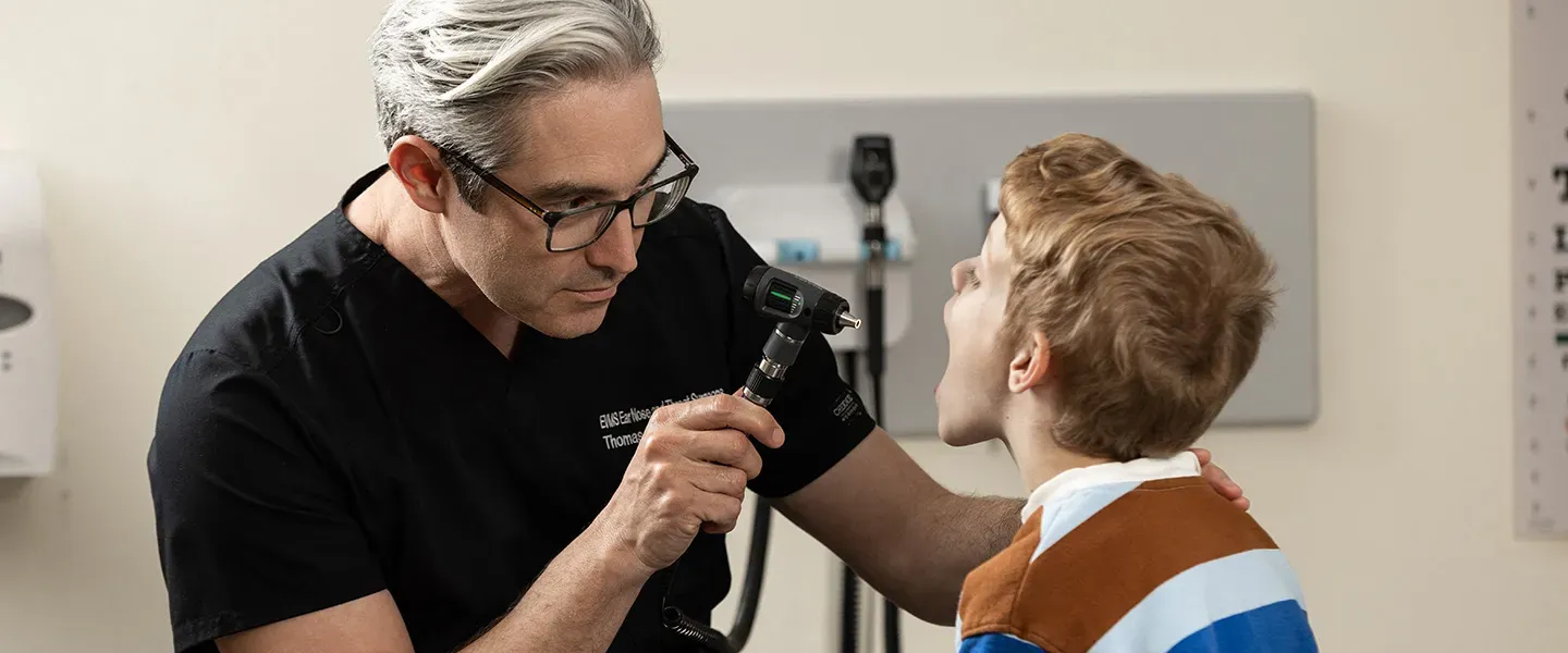A doctor examines a child's throat using a light.
