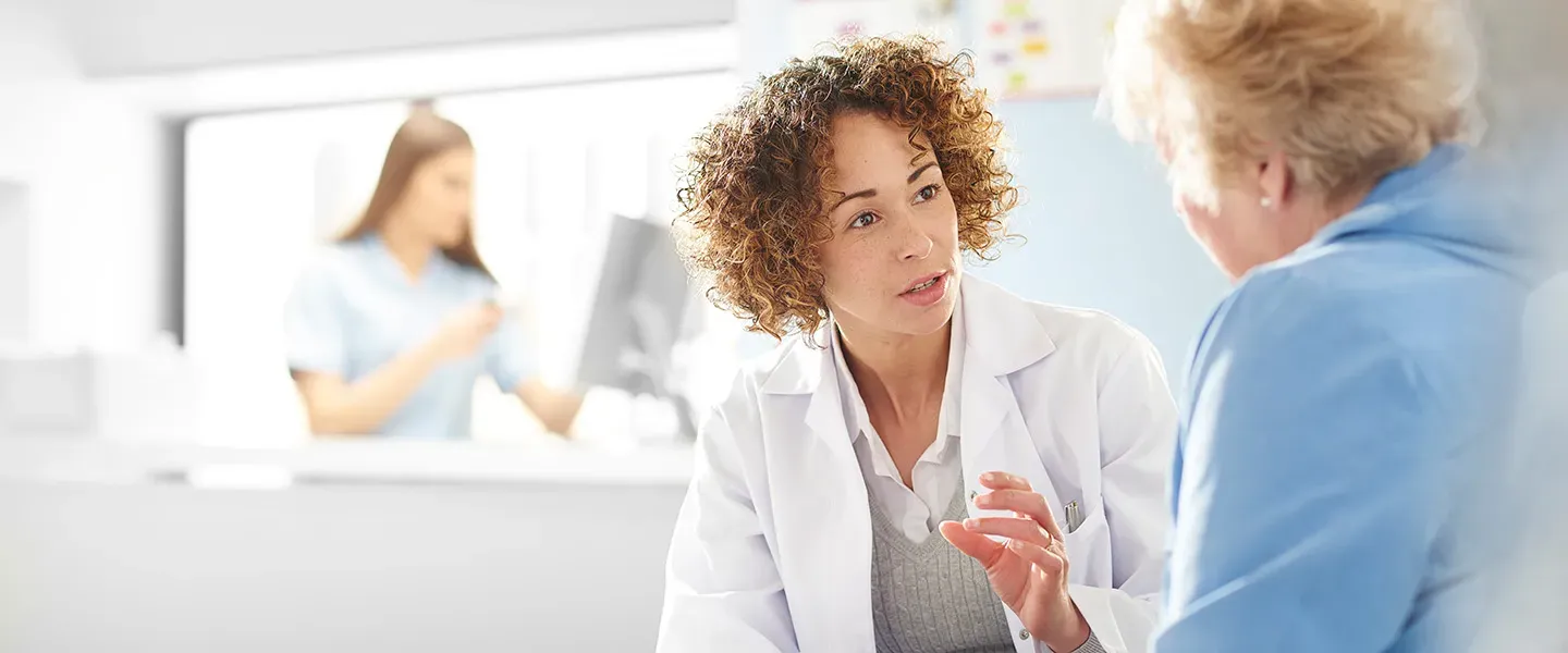 A psychiatrist with short curly hair wears a white medical c