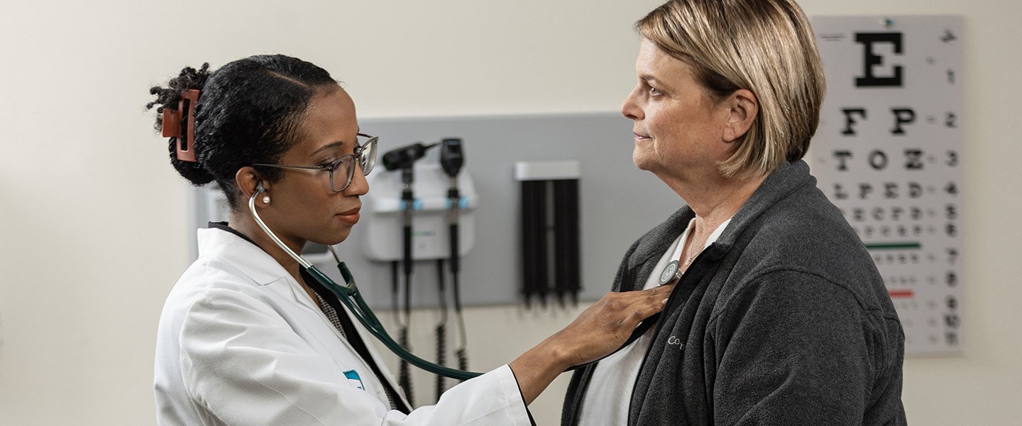 In a medical clinic, Dr. Gunther examines a patient by listening to her heart with a stethoscope.