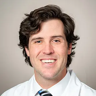 Dr. Bentz has short wavy brown hair, is wearing a white dres