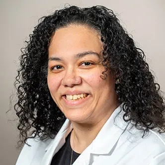 Jennifer Abdullah has long, dark curly hair, is wearing a bl