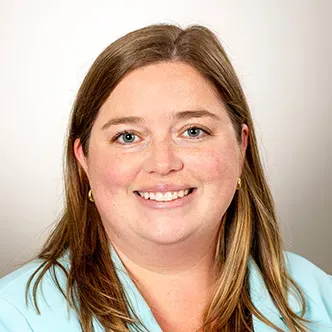 Dr. Dawson has long dark blonde hair, is wearing a light blu