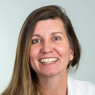 Dr. Lewis has long, straight, light brown hair, is wearing a