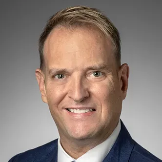 Mr. Lively has short blond hair, is wearing a dark suit and 