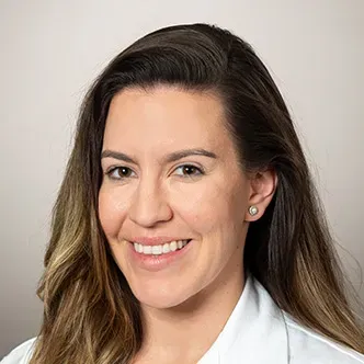 Dr. Olafson has long medium brown hair, is wearing a black b