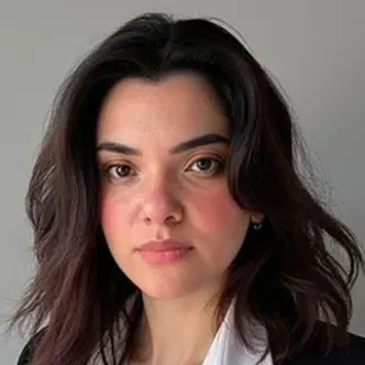 Dr. Osman has dark wavy hair, is wearing a white blouse unde