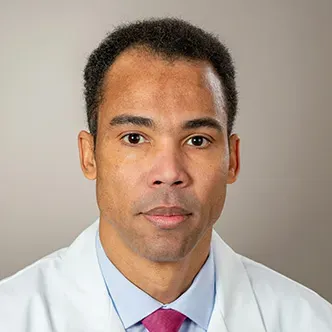 Dr. Tolentino has short dark hair, is wearing a blue shirt a