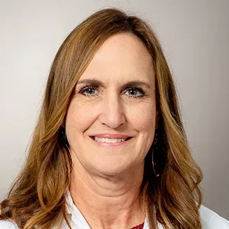 Janet Weir has long blonde hair parted on the side, is weari